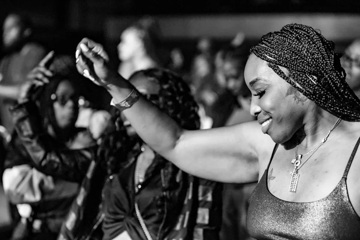 Attendee dancing with one arm raised while the crowd moves behind her
